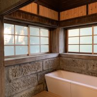 千葉県大網白里市南今泉の賃貸物件/浴室の様子。大きなバスタブに石組みの壁、擦りガラスの建具が印象的
