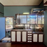 千葉県茂原市弓渡の賃貸物件/ノスタルジーなキッチンと壁のグレイの調和。キッチンはお勝手口つきで裏の公園のような空き地が見えて気分よし