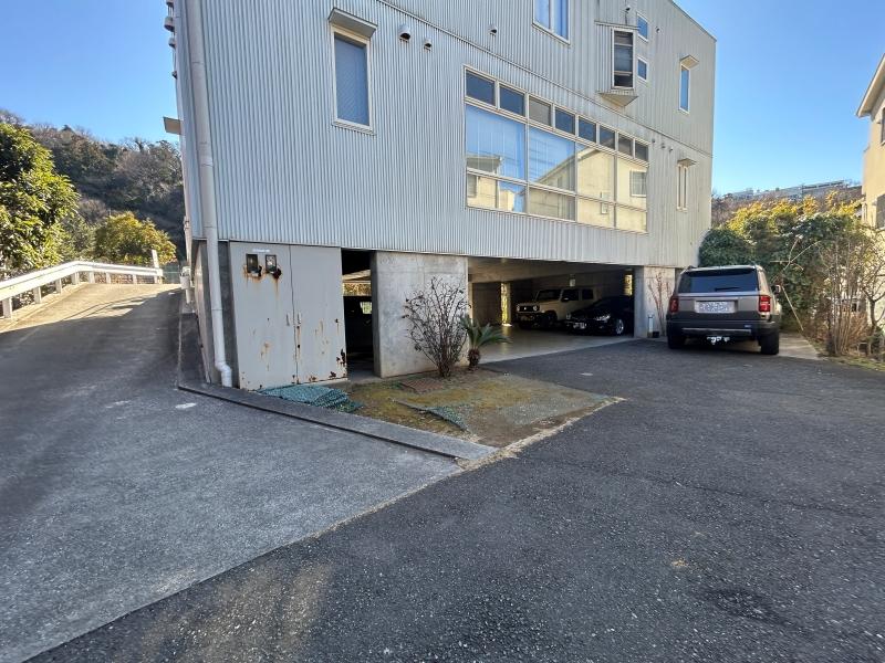 葉山町長柄の売買物件/アプローチ｜前面道路から左に写るスロープを下って敷地内へ。建物の外にも複数台の駐車スペースがあります