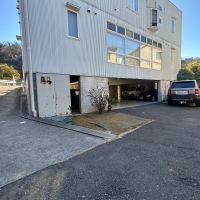 葉山町長柄の売買物件/アプローチ｜前面道路から左に写るスロープを下って敷地内へ。建物の外にも複数台の駐車スペースがあります
