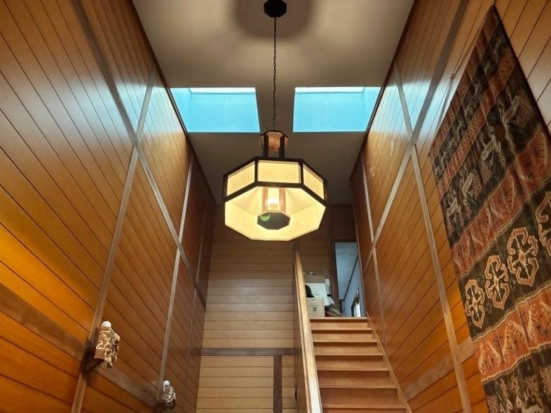 鎌倉市浄明寺一丁目の売買物件/玄関ホール｜建物に入るとまずはこの吹抜け。天井から吊るされた照明は松本民芸家具の逸品。勾配天井の際まできれいに張られた壁の板張りも含め、ゲストを圧倒する空間に仕立てています