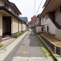 金沢市橋場町の賃貸物件/車１台が通れる幅の前面道路。左側に見える青色の建物が本物件。近隣には比較的新しいお家もちらほら