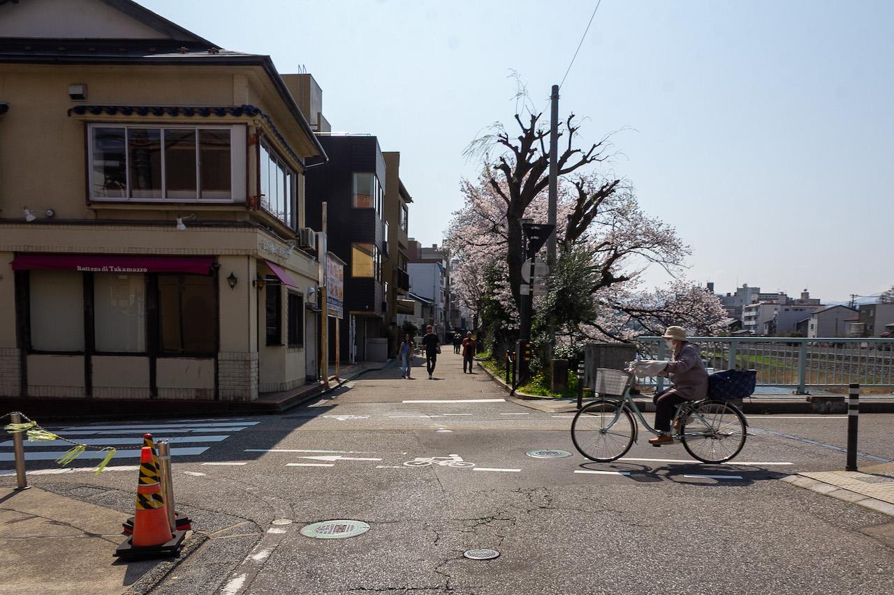 金沢市片町の賃貸物件/桜の時期に撮影した本物件：犀川と桜、新橋を行き交う地元住民、川沿いを歩く外国人観光客。これこそ、今の金沢らしい風景