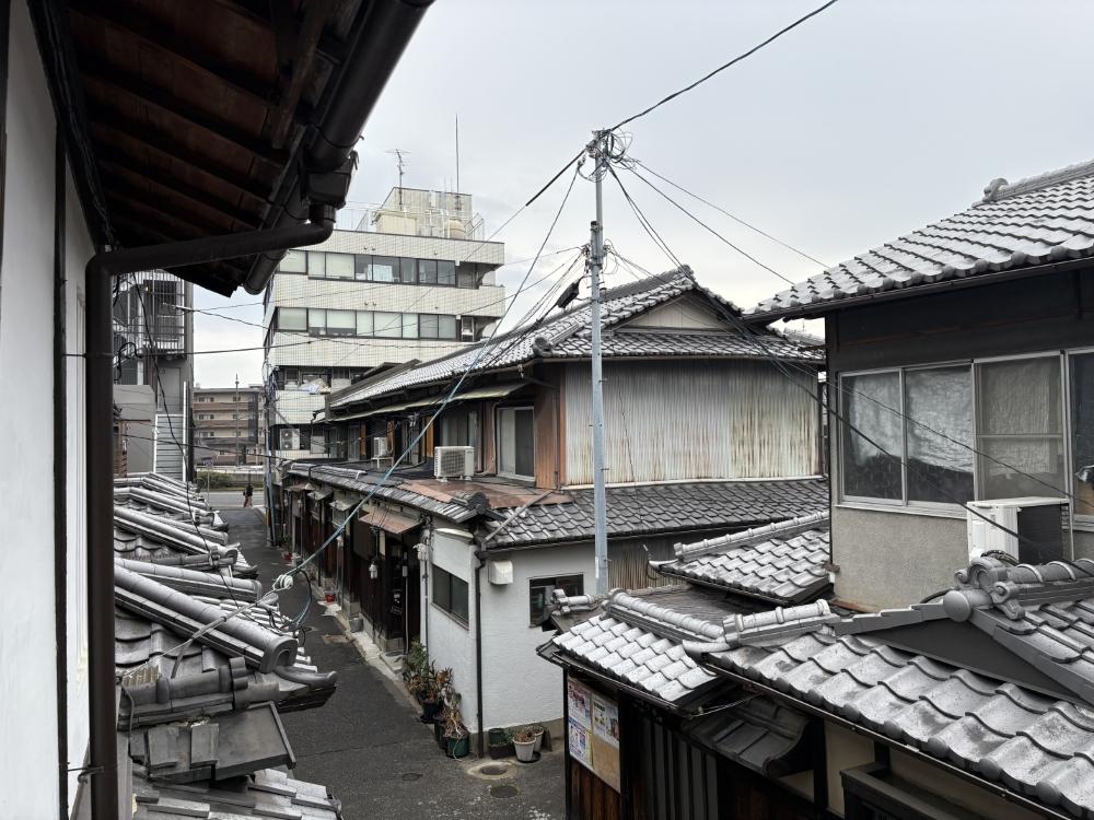 京都市東山区五条橋東の賃貸物件/2階西の開口から｜近隣長屋の瓦屋根が連なる。先に見えるのが五条通り