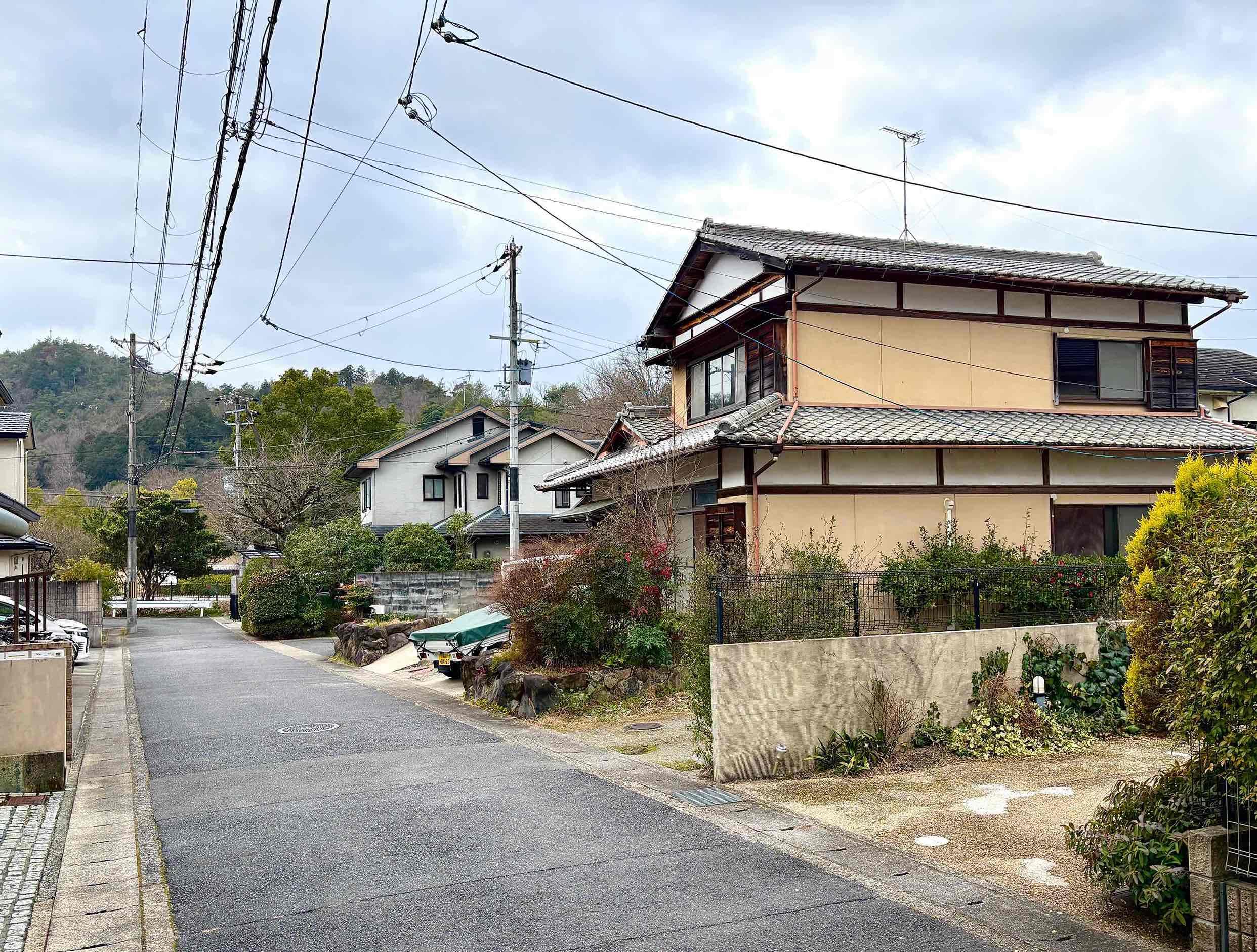 京都市左京区上高野石田町の賃貸物件/前面道路の車の往来はかなり少ないのでお子さんが居ても安心。先に見える緑が宝ヶ池公園