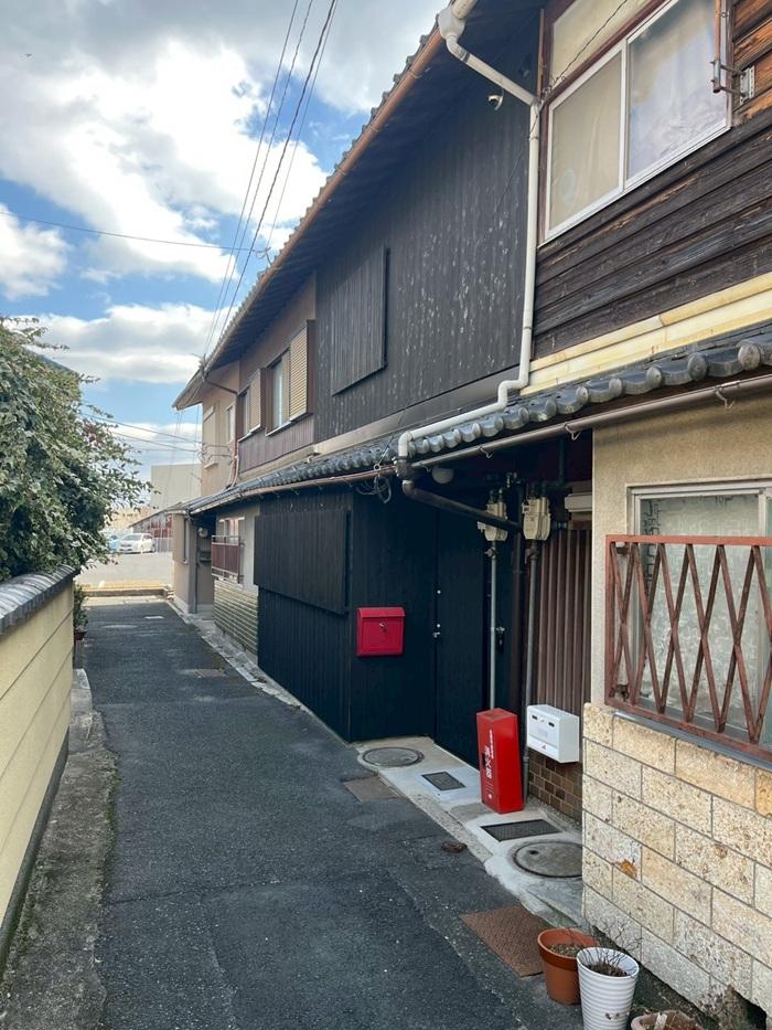 滋賀県大津市尾花川の売買物件/該当物件は4連棟の真ん中。路地を抜けると近隣店舗の駐車場へ続いている。