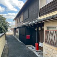 滋賀県大津市尾花川の売買物件/該当物件は4連棟の真ん中。路地を抜けると近隣店舗の駐車場へ続いている。