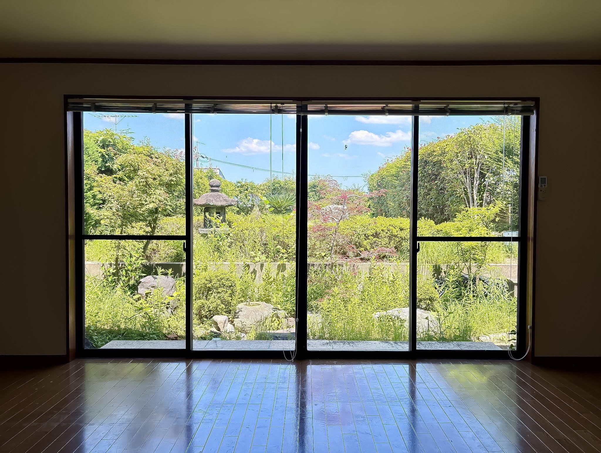 京都市西京区御陵北山町33-4の賃貸物件/リビングの一部に感じるほど窓いっぱいに広がる庭の緑。雑草もちらほら生えていますがご入居前に剪定予定です。