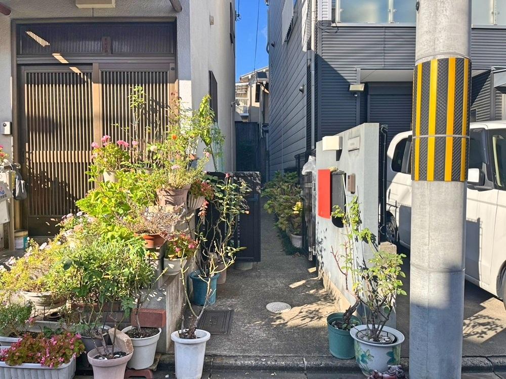 京都市上京区御前通仁和寺街道下る三筋目東入る西上之町278-5の賃貸物件/前道からは々の鉢植えが並ぶこの細い通路を入って行きます。