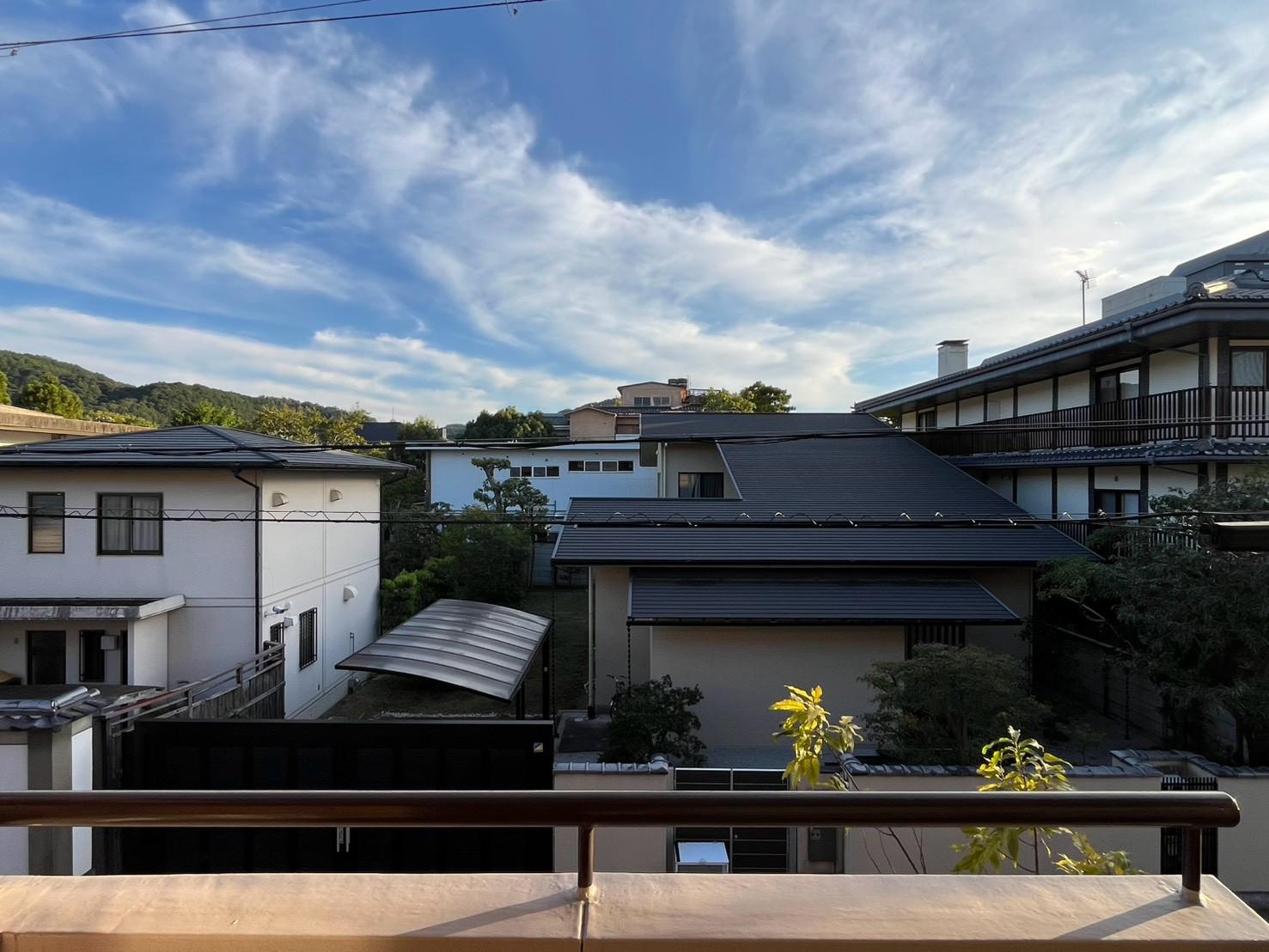 京都市左京区岡崎天王町43の賃貸物件/バルコニーからの眺め。低層住宅の屋根の向こうには山並みと広い空。