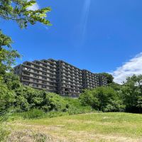 埼玉県入間市仏子の売買物件/川側からマンションを見上げて。芝生の気持ちいい広場がある