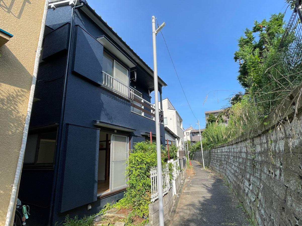 板橋区赤塚の賃貸物件/曲がりくねった味のある小道。建物の外装はキレイなネイビーで塗装されています