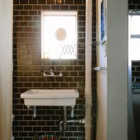 千葉県美浜区幸町の売買物件/むき出しの配管が活きるタイル張りのトイレ空間。小さな窓もどこか海外のアパルトマンのよう
