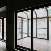 渋谷区神宮前の賃貸物件/室内から見る、アーチ屋根のサンルーム。その奥に平板張りの庭（103号室）
